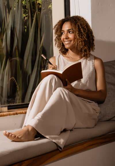 Woman with curly hair smiling and journaling