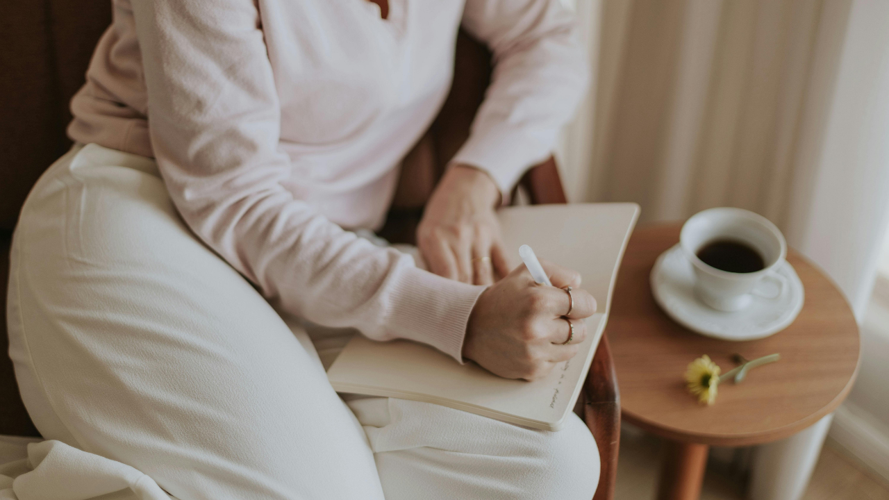 Business owner writing in journal with coffee Business owner writing in journal with coffee